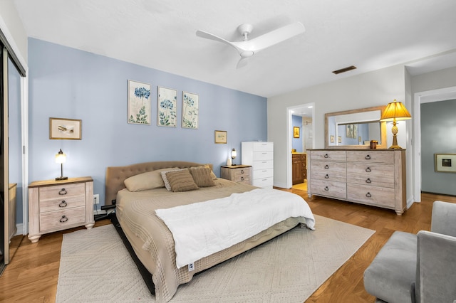 bedroom featuring hardwood / wood-style floors, ensuite bath, a closet, and ceiling fan