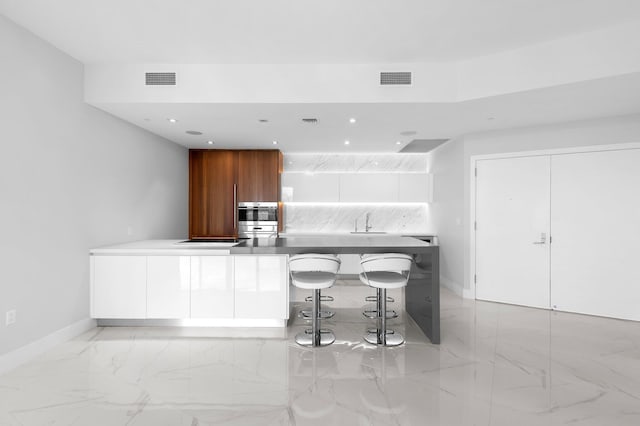 kitchen with visible vents, decorative backsplash, a peninsula, marble finish floor, and modern cabinets