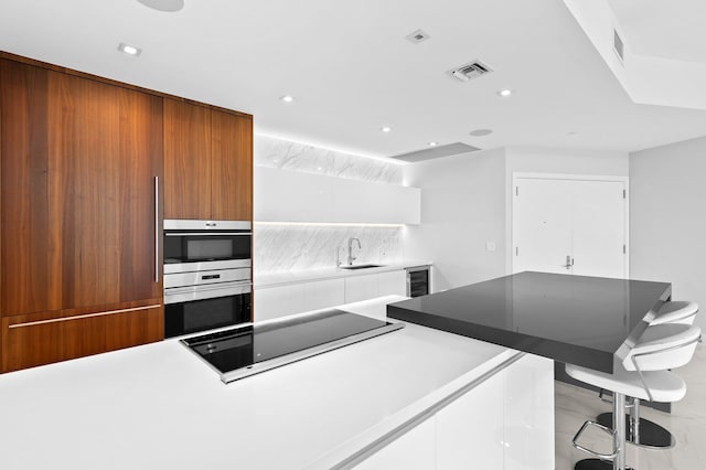 701 N Fort Lauderdale Beach Blvd Unit 504, Fort Lauderdale, FL 33304 - kitchen featuring black electric cooktop, modern cabinets, beverage cooler, white cabinets, and brown cabinetry
