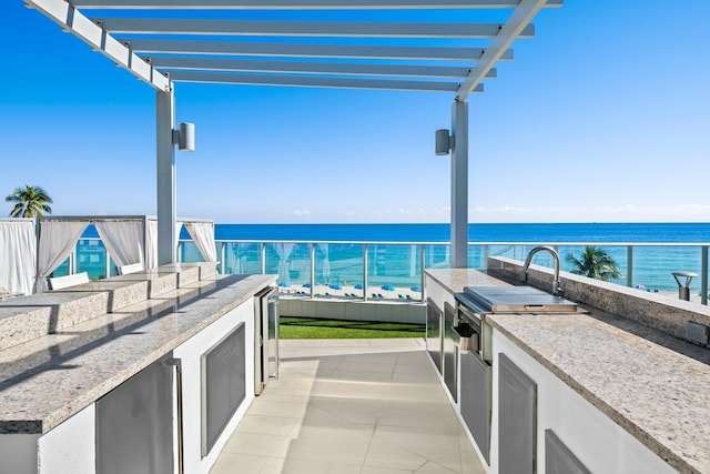 view of patio / terrace with a water view, area for grilling, beverage cooler, and a pergola