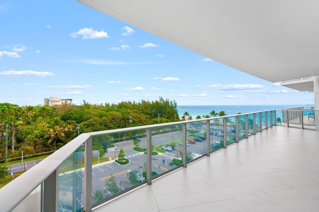 balcony featuring beverage cooler, a water view, and exterior kitchen