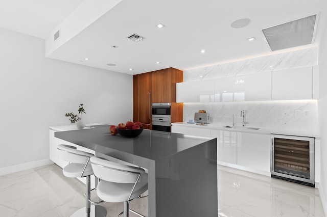 kitchen with visible vents, modern cabinets, marble finish floor, and a sink