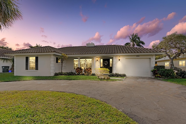 mediterranean / spanish house featuring a garage and a lawn