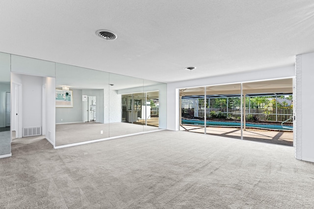 unfurnished living room with carpet flooring and a textured ceiling