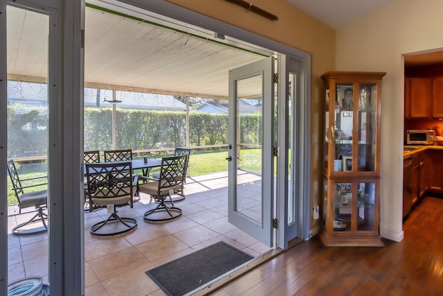 doorway to outside with tile patterned flooring and vaulted ceiling