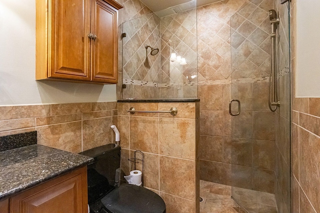 bathroom featuring walk in shower, vanity, and tile walls