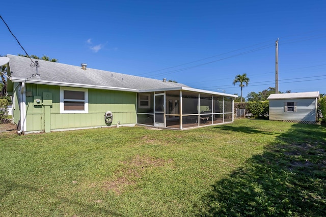 back of property featuring a sunroom, a yard, and a shed