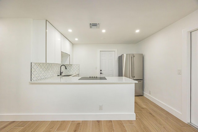 kitchen featuring white cabinetry, high end refrigerator, kitchen peninsula, and sink