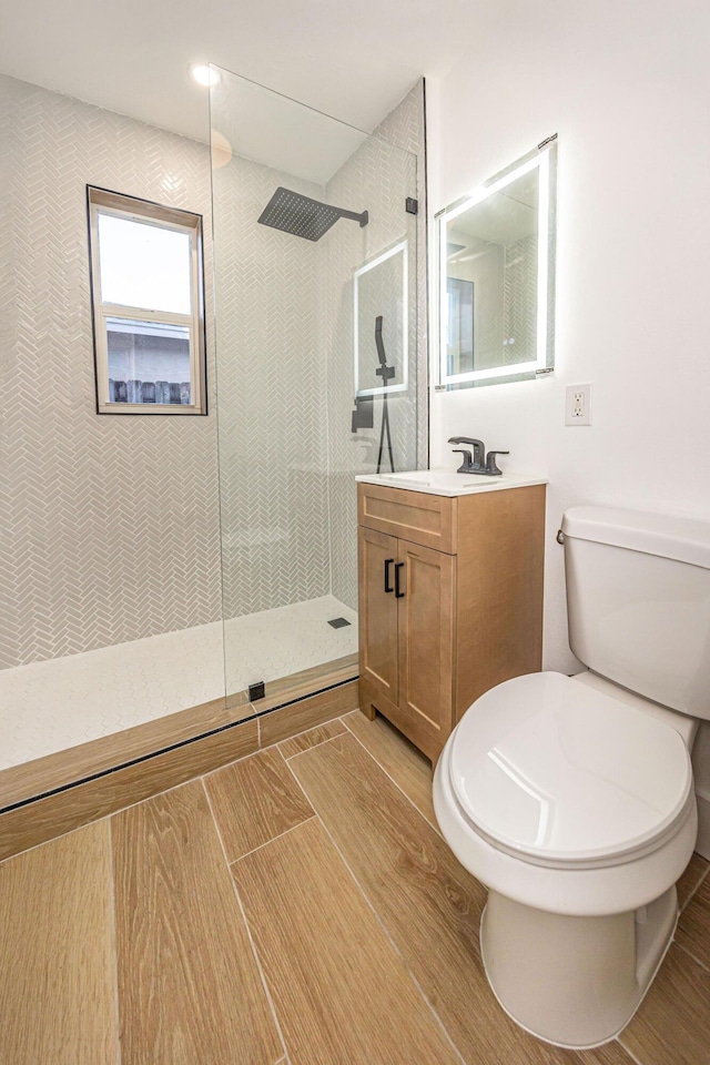 bathroom featuring vanity, a tile shower, and toilet