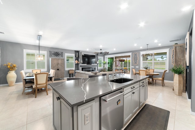 kitchen featuring stainless steel dishwasher, an inviting chandelier, light tile patterned floors, and a sink