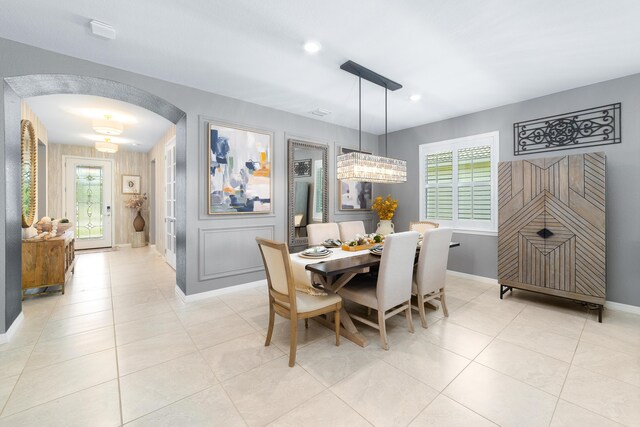 dining room with plenty of natural light, baseboards, arched walkways, and light tile patterned floors
