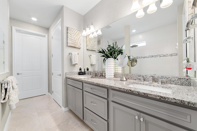 full bathroom with a sink, tiled shower, double vanity, and tile patterned flooring