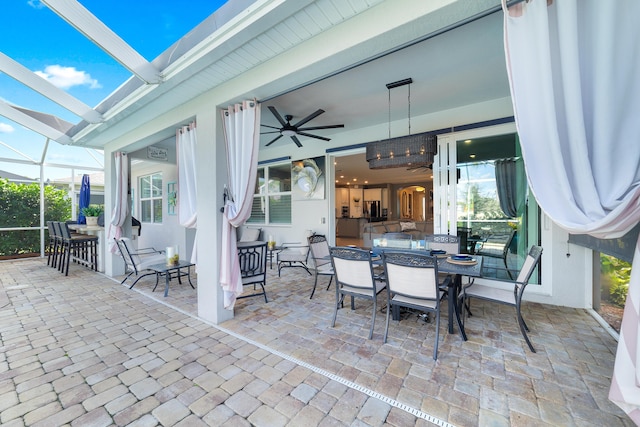 view of patio featuring a lanai, outdoor dining area, and ceiling fan