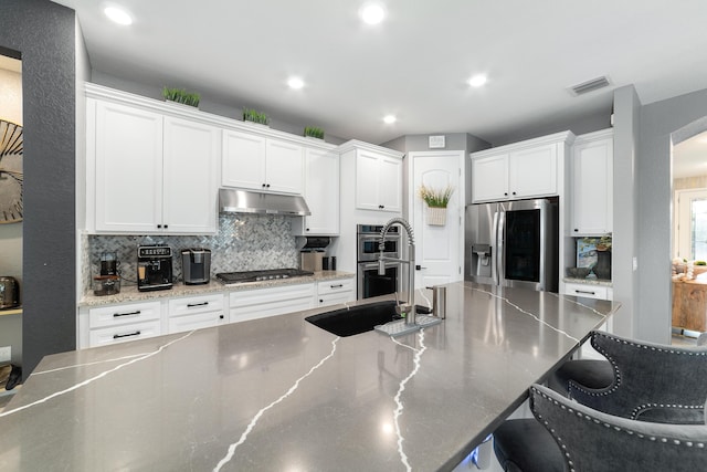 kitchen with visible vents, under cabinet range hood, tasteful backsplash, white cabinetry, and stainless steel appliances