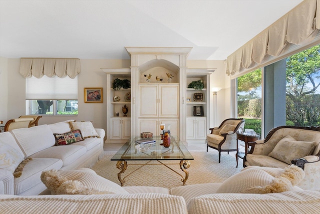 living room with lofted ceiling, built in features, and a healthy amount of sunlight