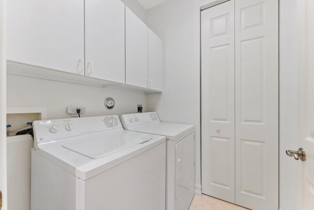 laundry room with cabinets, washer and clothes dryer, and light tile patterned floors