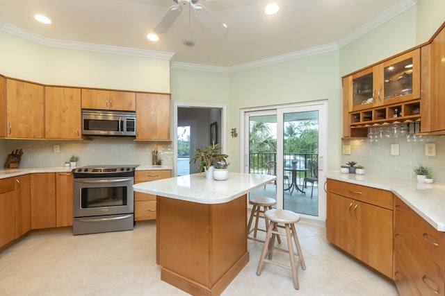 kitchen with appliances with stainless steel finishes, a center island, brown cabinetry, and light countertops