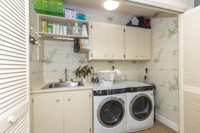 laundry room featuring light wood-type flooring, cabinet space, a sink, and washer and clothes dryer