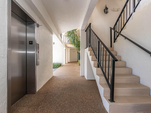 stairs with a textured wall and elevator