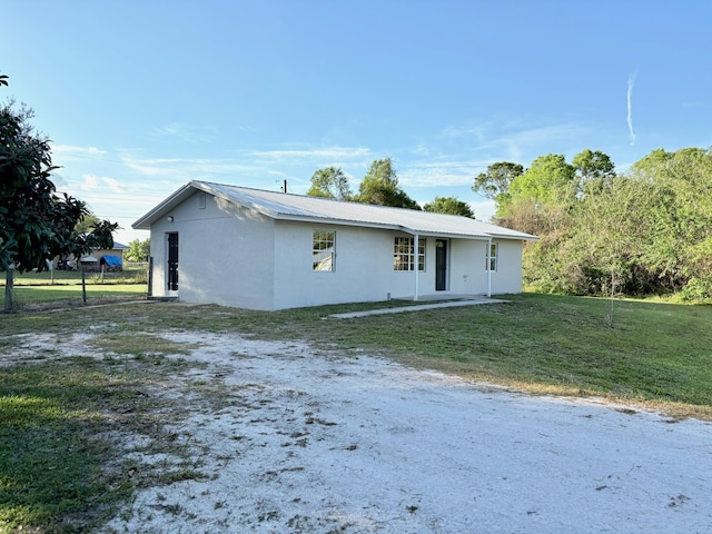 view of front of house with a front yard, metal roof, and stucco siding