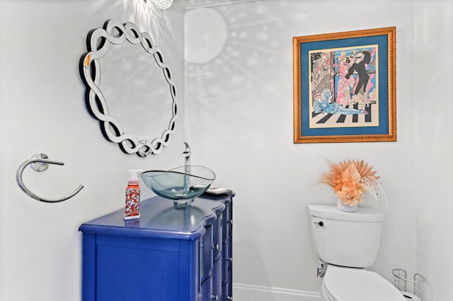 bathroom featuring baseboards, vanity, and toilet