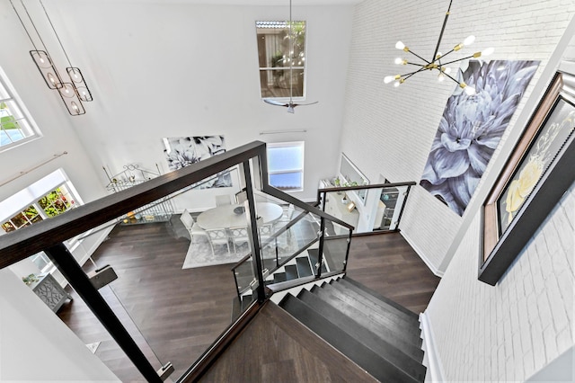 stairway featuring an inviting chandelier, a high ceiling, and wood finished floors