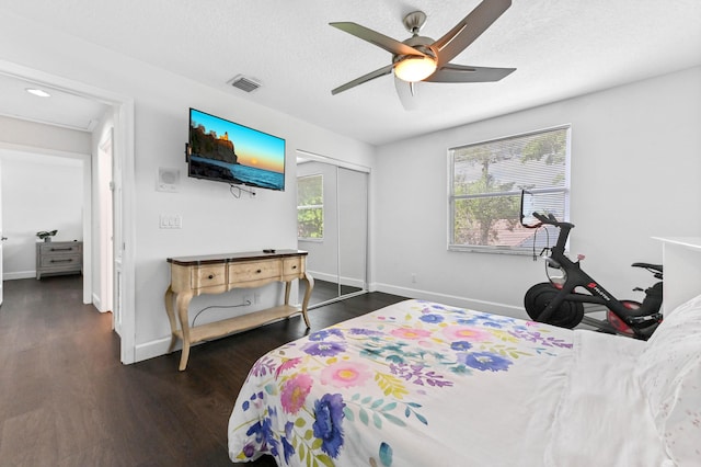 bedroom featuring dark wood-style floors, a closet, visible vents, a textured ceiling, and baseboards