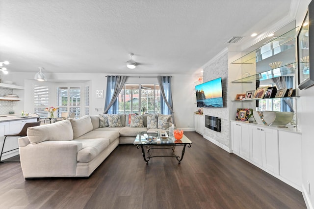 living room with a textured ceiling, a fireplace, dark wood finished floors, and visible vents