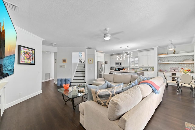 living area with dark wood-style flooring, visible vents, stairway, and a textured ceiling