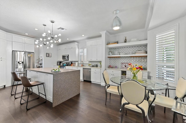 kitchen featuring a kitchen island, appliances with stainless steel finishes, open shelves, and light countertops