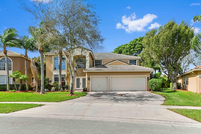 view of front facade with driveway, stucco siding, an attached garage, and a front yard