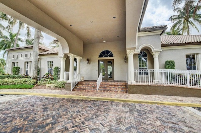 property entrance with french doors, a tiled roof, and stucco siding