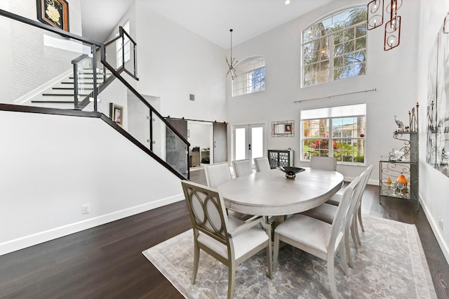 dining space featuring a towering ceiling, baseboards, french doors, stairway, and dark wood-style floors