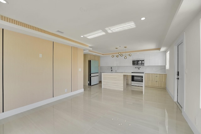 kitchen featuring black microwave, white cabinets, hanging light fixtures, fridge, and range