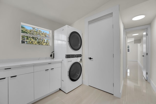 clothes washing area with stacked washer and dryer and cabinets