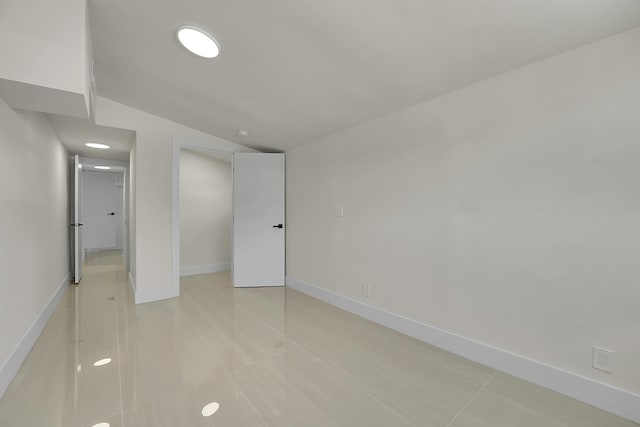 tiled empty room with lofted ceiling