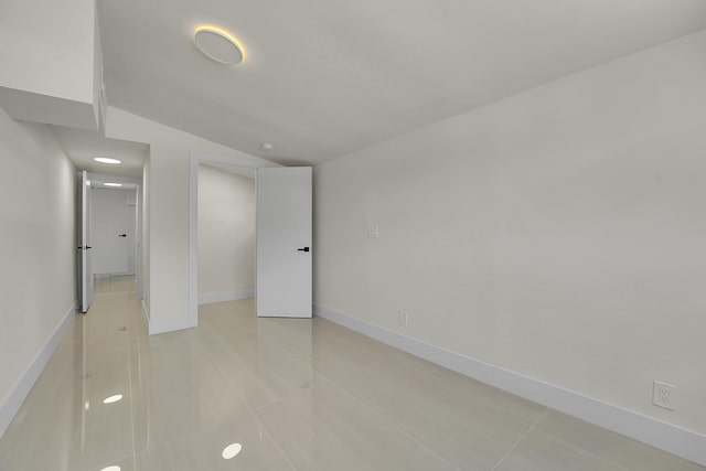 empty room featuring lofted ceiling and light tile patterned floors