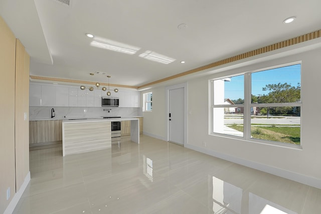 kitchen featuring pendant lighting, decorative backsplash, a kitchen island, and white cabinets