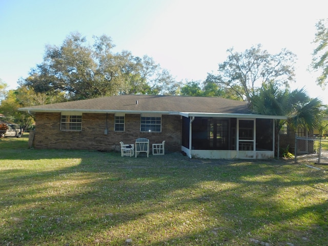 rear view of house featuring a lawn and a sunroom