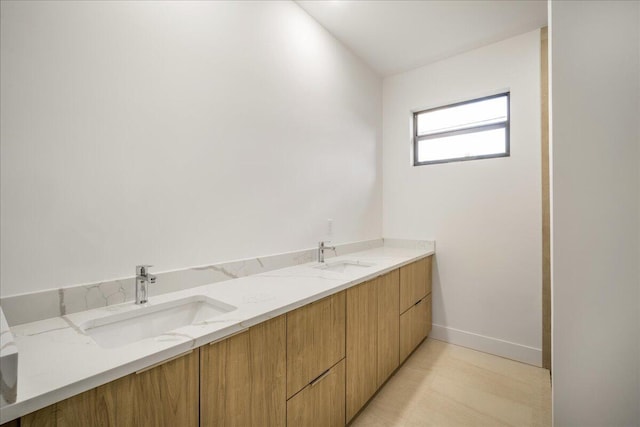 bathroom featuring double vanity, a sink, and baseboards