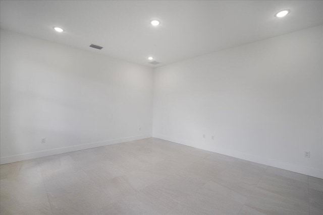 empty room featuring baseboards, visible vents, and recessed lighting