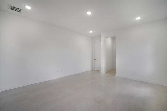 empty room with recessed lighting, visible vents, and baseboards