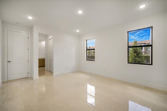 spare room with recessed lighting and baseboards