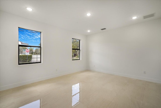 spare room with plenty of natural light, visible vents, and baseboards
