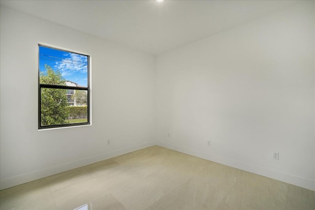 spare room featuring light floors and baseboards