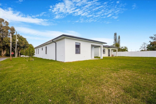 back of property featuring a lawn, fence, and stucco siding