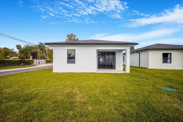 back of property with stucco siding and a yard
