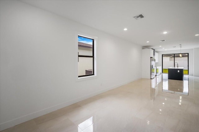 spare room featuring recessed lighting, a sink, visible vents, and baseboards