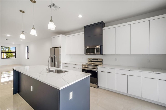 kitchen featuring decorative light fixtures, a center island with sink, stainless steel appliances, visible vents, and a sink
