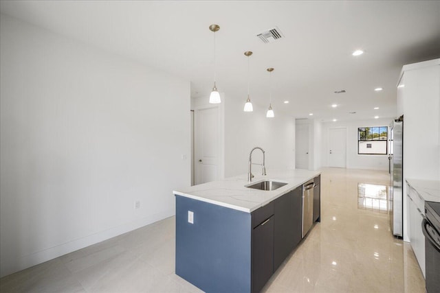 kitchen with a barn door, visible vents, an island with sink, pendant lighting, and a sink